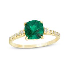 a green cushion cut ring with diamonds on the band and an emerald colored stone in the center