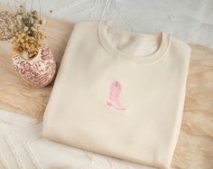 a white t - shirt with a pink heart on it next to a flower pot