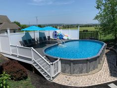 an above ground swimming pool with steps leading up to the deck and umbrellas over it