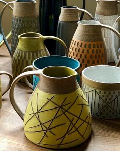 many different colored vases sitting on top of a wooden table next to each other