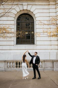 a bride and groom dancing in front of a building