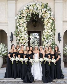 a group of women standing next to each other in front of a white and black arch