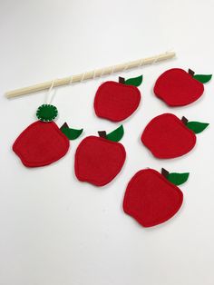 red felt apples with green leaves on white background