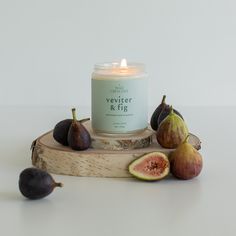 a candle sitting on top of a piece of wood next to figs