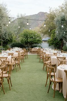 tables and chairs set up for an outdoor wedding reception with string lights strung over them