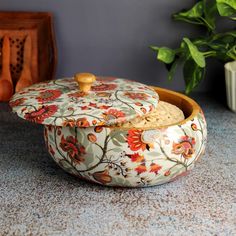 a bowl with a lid sitting on top of a counter next to a potted plant