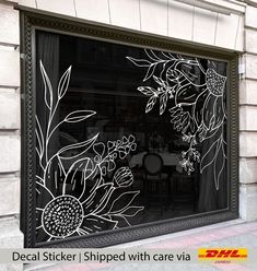 a window with flowers drawn on it in front of a brick building and the words decal sticker shipped with care via