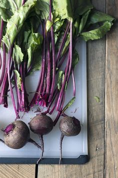 turnips with green leaves and purple stems on a cutting board