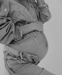 a pregnant woman wearing jeans and holding her stomach