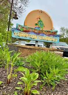 there is a sign that says comption gardens in front of the parking lot