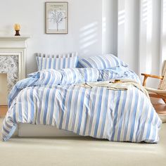 a bed with blue and white striped comforter next to a fireplace in a room