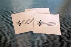 two envelopes with musical notes on them sitting on a table next to each other