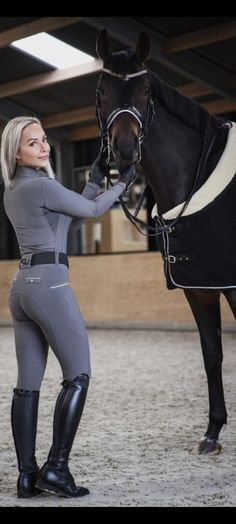 a woman standing next to a black horse