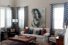 a living room with couches, chairs and rugs in front of two windows