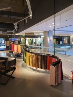 the interior of a clothing store with clothes on racks in front of glass walls and an indoor swimming pool