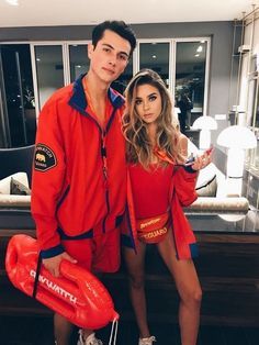 a man and woman in red outfits posing for a photo with an orange life preserver