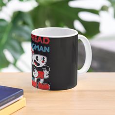 a black and white coffee mug sitting on top of a table next to a book