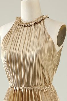 a gold dress on a mannequin dummy with an open back and pleated neckline