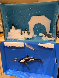 an orca whale swims in the water near icebergs and snow on display