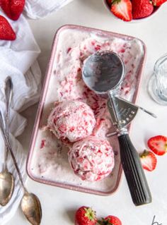 strawberry ice cream with spoons and bowls of strawberries