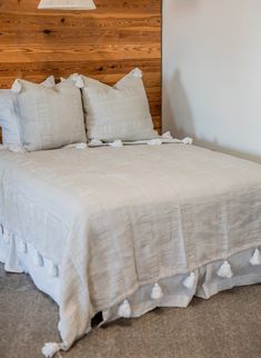 a bed with two pillows on top of it next to a wooden headboard and lamp