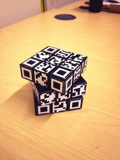 three black and white cubes sitting on top of a wooden table