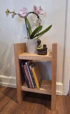 a small wooden shelf with flowers and books on it