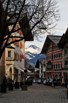 a cobblestone street with buildings and mountains in the background