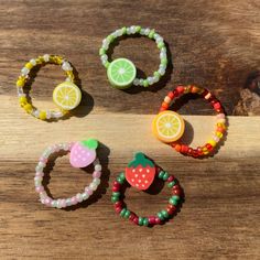 four fruit and beaded bracelets sitting on top of a wooden table next to each other