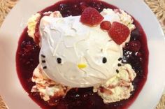 a white plate topped with ice cream covered in berries and a hello kitty face on top