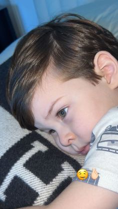 a young boy laying on top of a bed