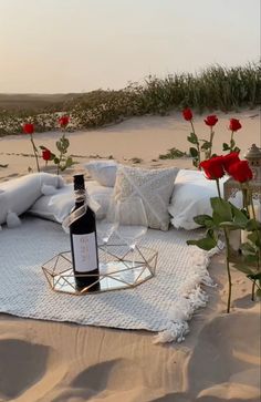 a bottle of wine sitting on top of a white blanket next to flowers and pillows