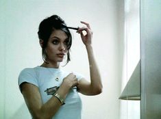 a woman is brushing her hair in front of a window with a lamp on the side