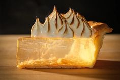 a piece of pie with whipped cream on top sitting on a wooden table in front of a black background