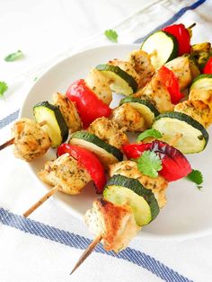 grilled chicken and vegetable kabobs on a white plate with blue and white table cloth