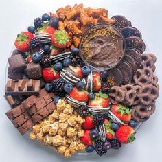 a platter filled with chocolate, strawberries, pretzels and other snacks