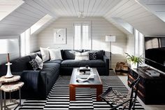 a living room with black couches and white walls