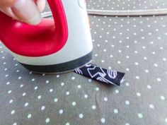 a person is using an iron on a polka dot tablecloth with a black and white ribbon