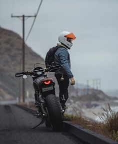 a man standing next to his motorcycle on the road