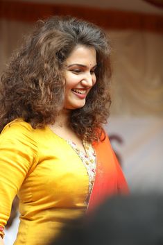 a woman with curly hair smiling and holding a cell phone