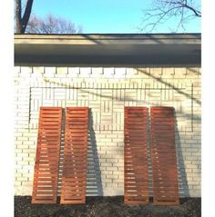 three wooden slats are lined up against a brick wall in front of a tree