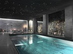 an indoor swimming pool with lights on the ceiling and water running down the side wall