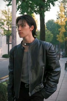 a man standing on the sidewalk wearing a black leather jacket