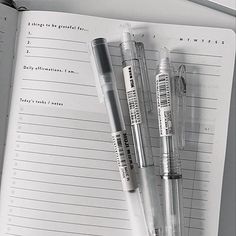 two pens sitting on top of an open notebook