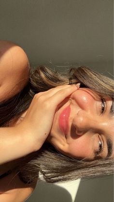 a woman with her hand on her face and the sun shining down behind her head