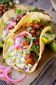 three tacos with onions, lettuce and other toppings