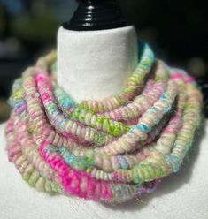 a white mannequin with multicolored knitted necklaces on it's neck