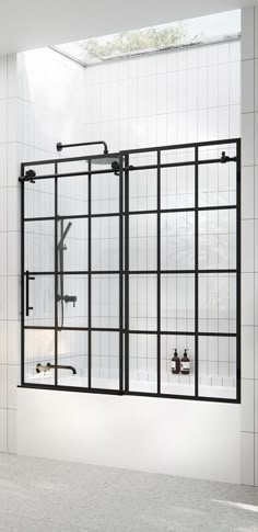 a white tiled bathroom with an open glass shower door and black metal fixtures on the wall