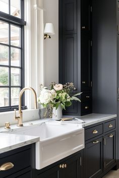 a white sink sitting under a window next to a black cupboards and counter top