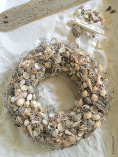 a wreath made out of sea shells sits on a piece of paper next to a sign